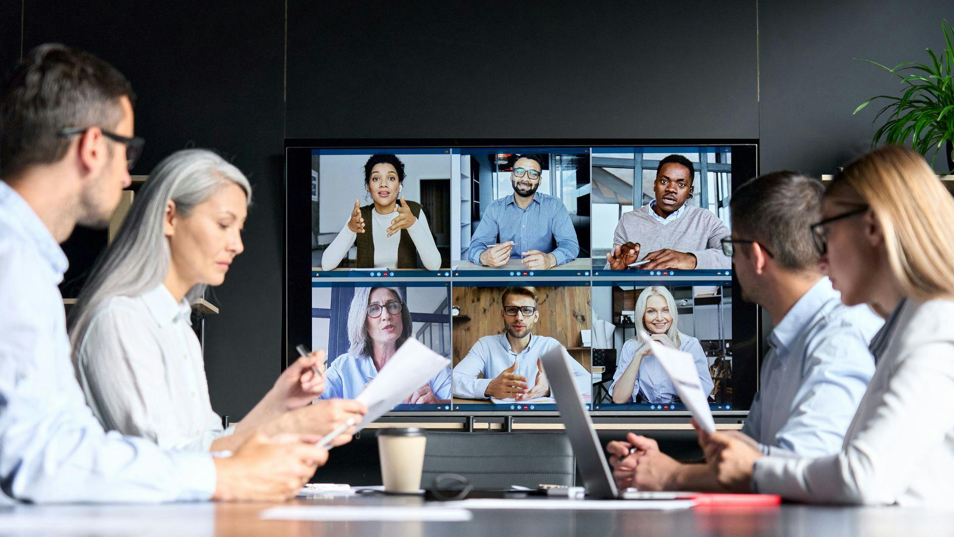 A diverse group of professionals engaged in a video conference, collaborating in a conference room.