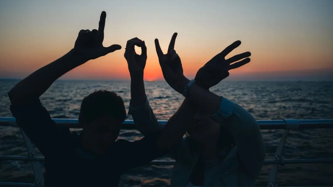 A group of people making hand gestures that spell 'LOVE'