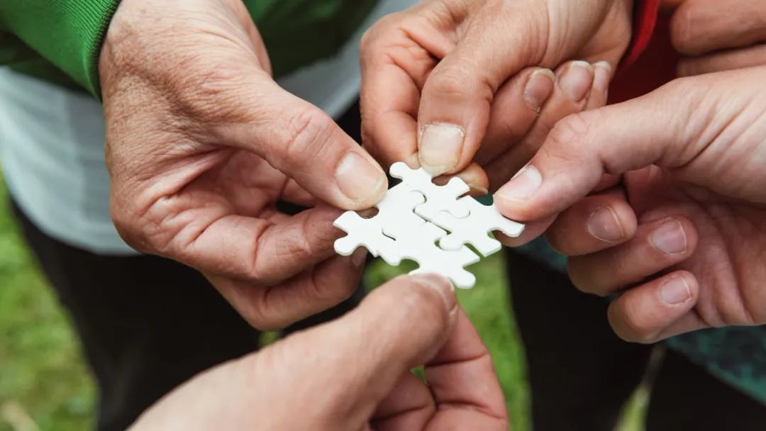 A group of hands holding a piece of puzzle