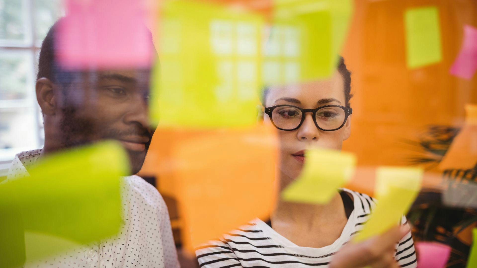 A woman and man in the office looking at various sticky notes