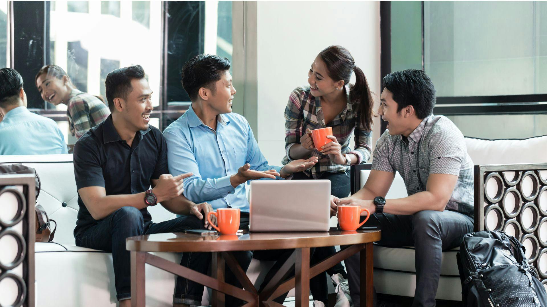 a group of people sitting around a table, happily collaborating at work