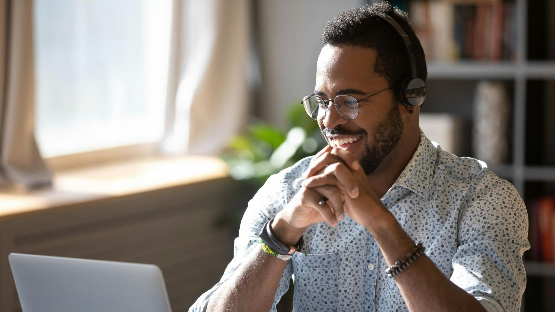 remote worker wearing headphones and smiling in front of their laptop