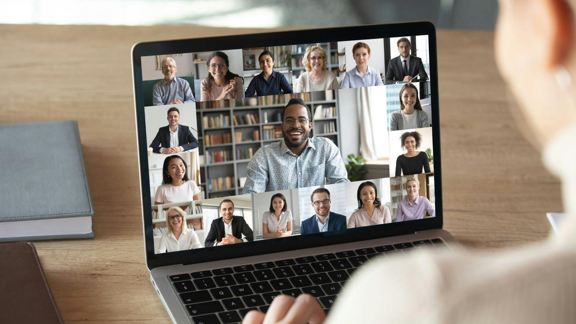 Someone working from a laptop, viewing a group of people on their screen in a remote meeting