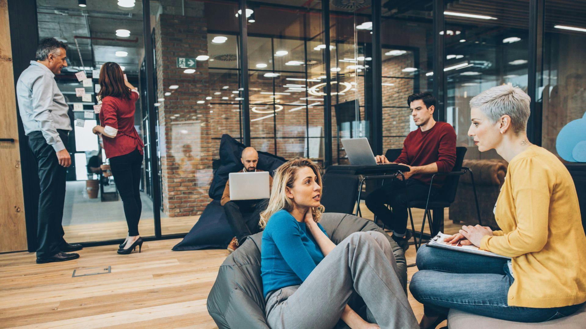 Group of individuals relaxing on bean bags in an office.