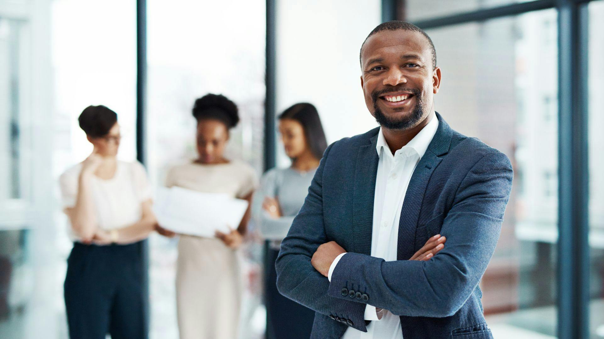 Confident African American businessman posing with his diverse team, showcasing leadership and teamwork in a corporate environment.