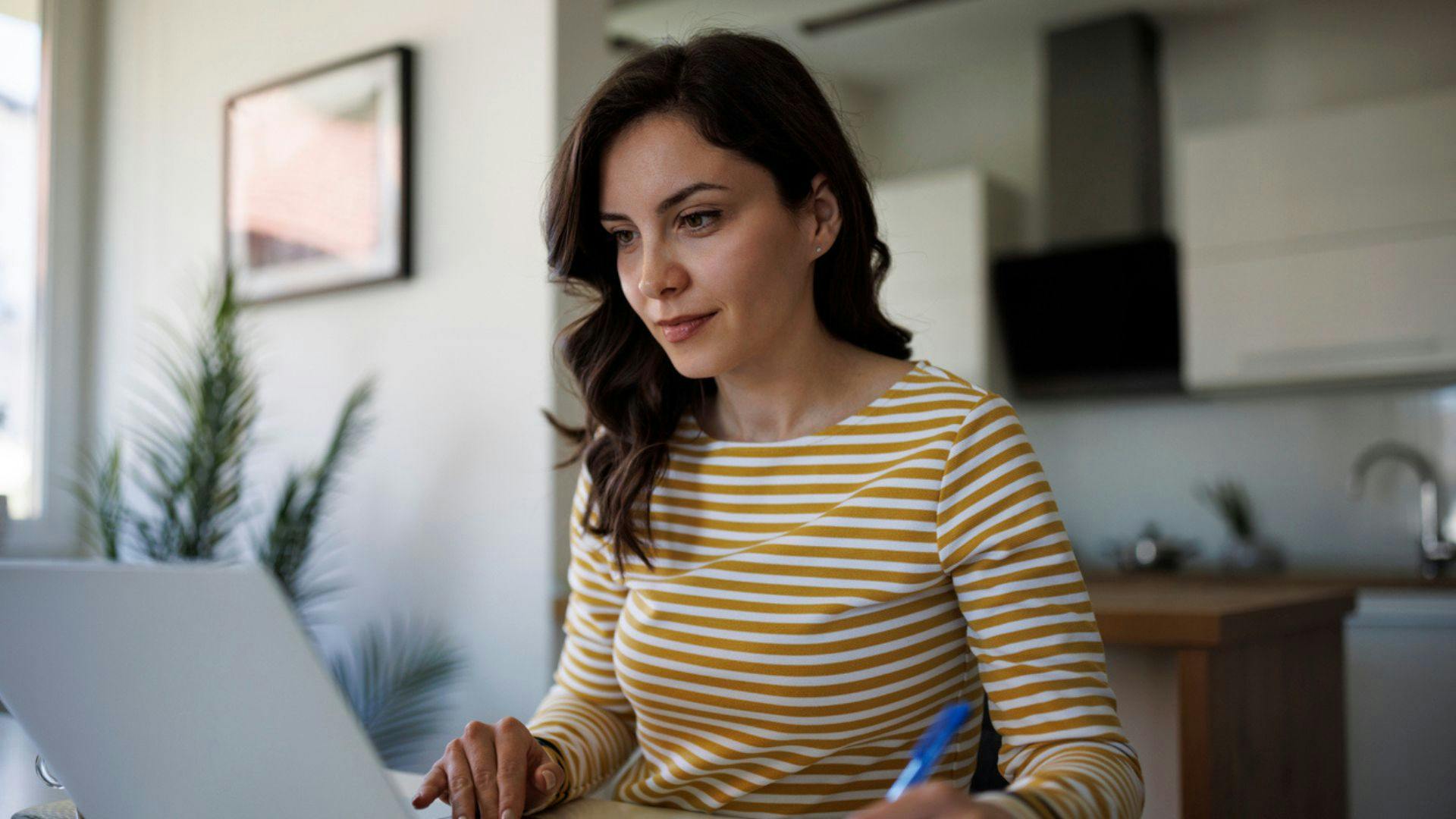Woman in striped shirt typing on laptop.