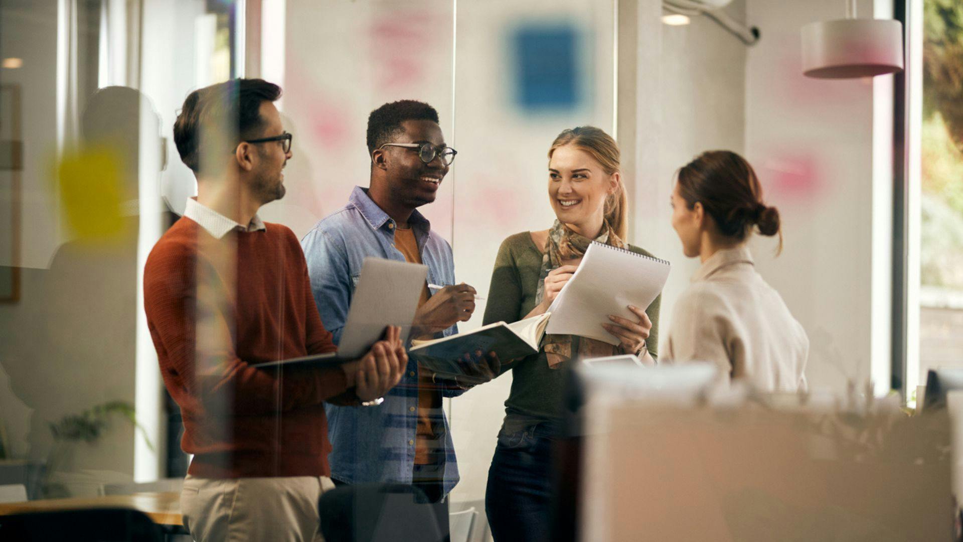 Colleagues engaged in conversation in a corporate office environment.