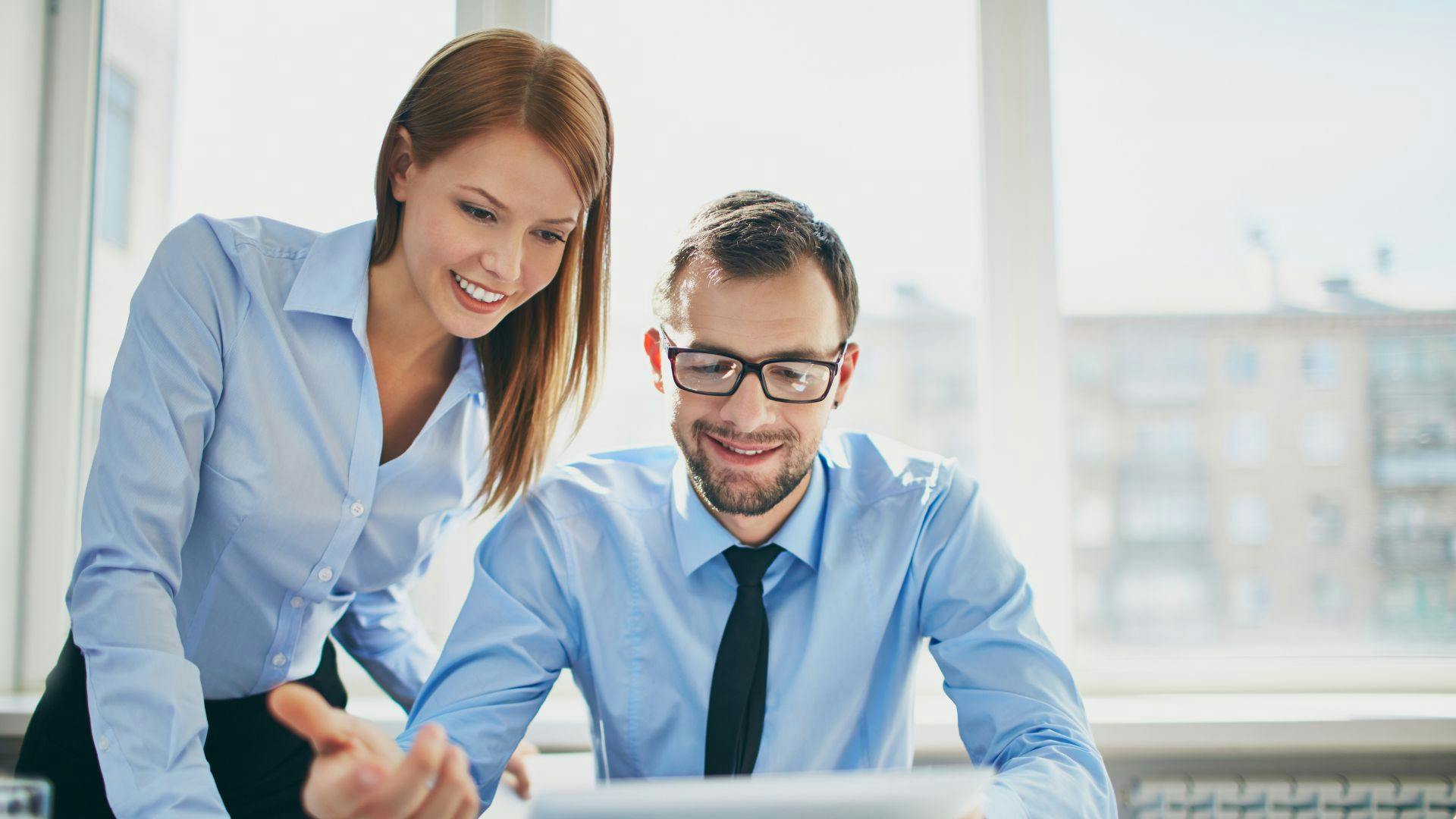 Professional man and woman reviewing something together on a tablet device.