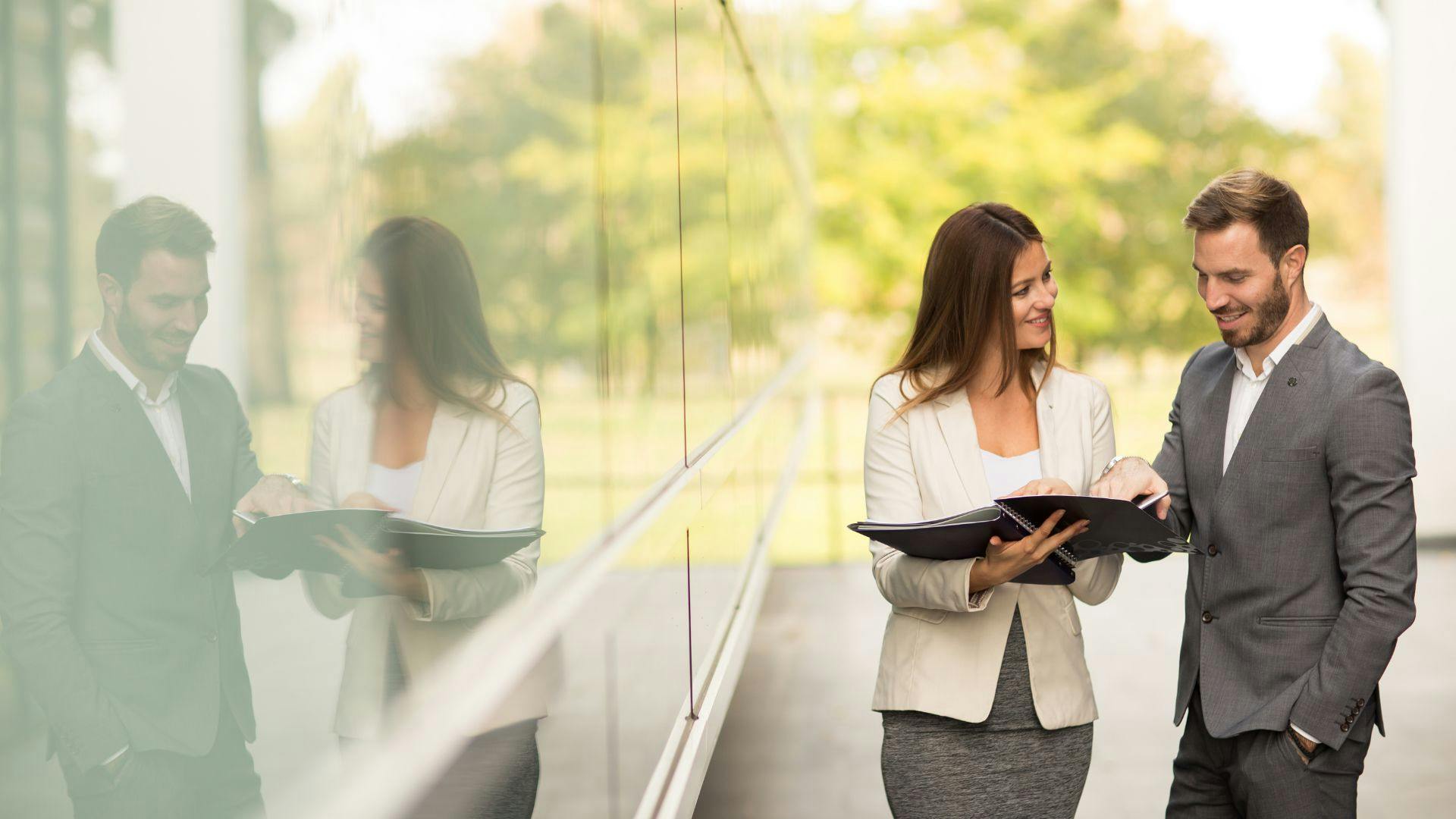 Two business individuals positioned in front of a corporate building, discussing strategies and opportunities.