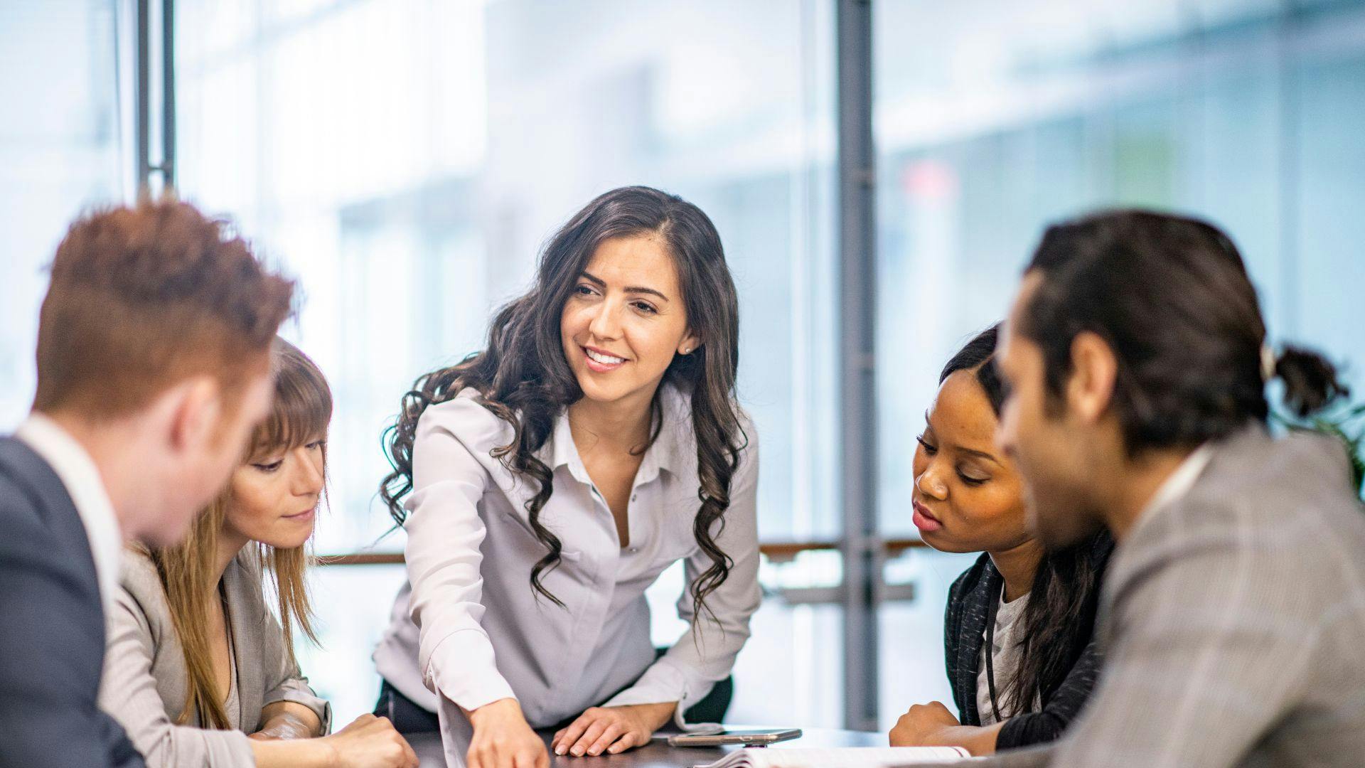 Business team members collaborating and sharing ideas while seated around a large table in a professional environment.