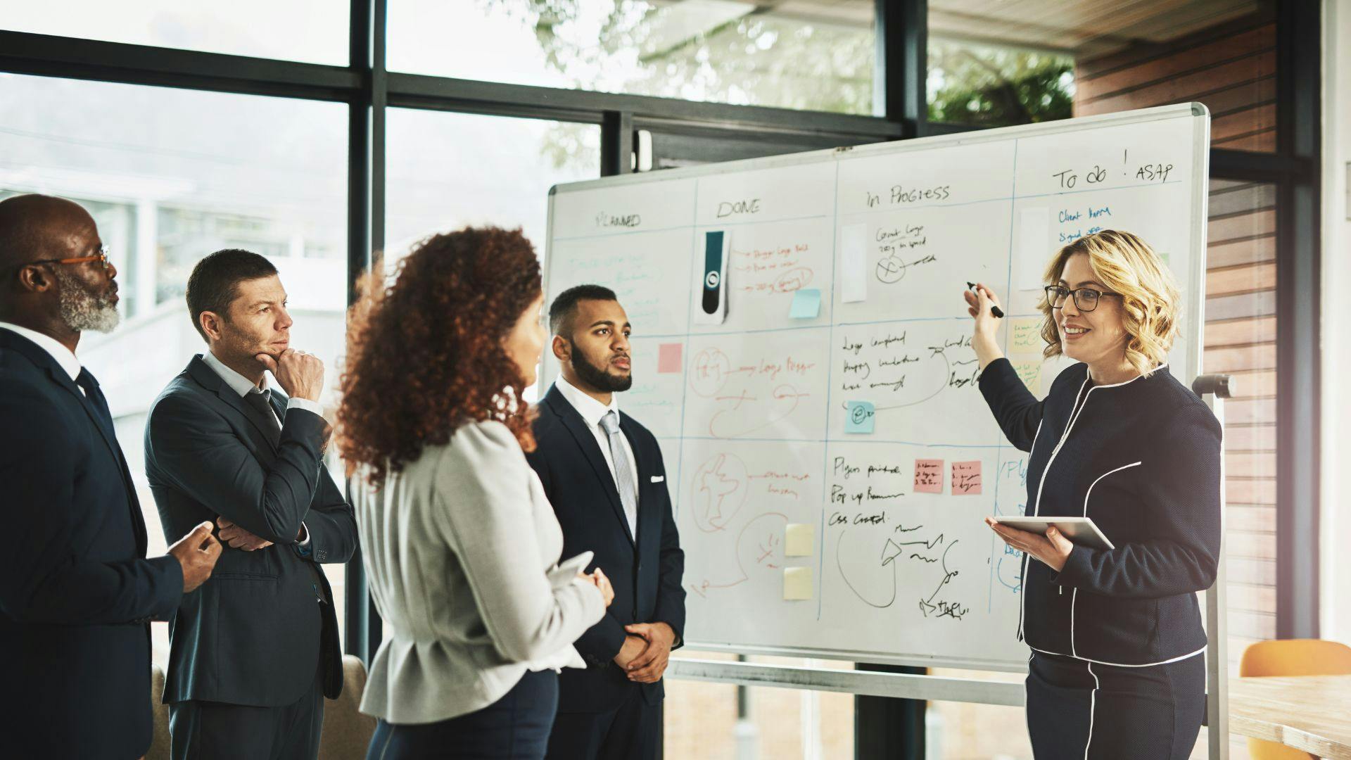 Business colleagues brainstorming together at a whiteboard during a team meeting.