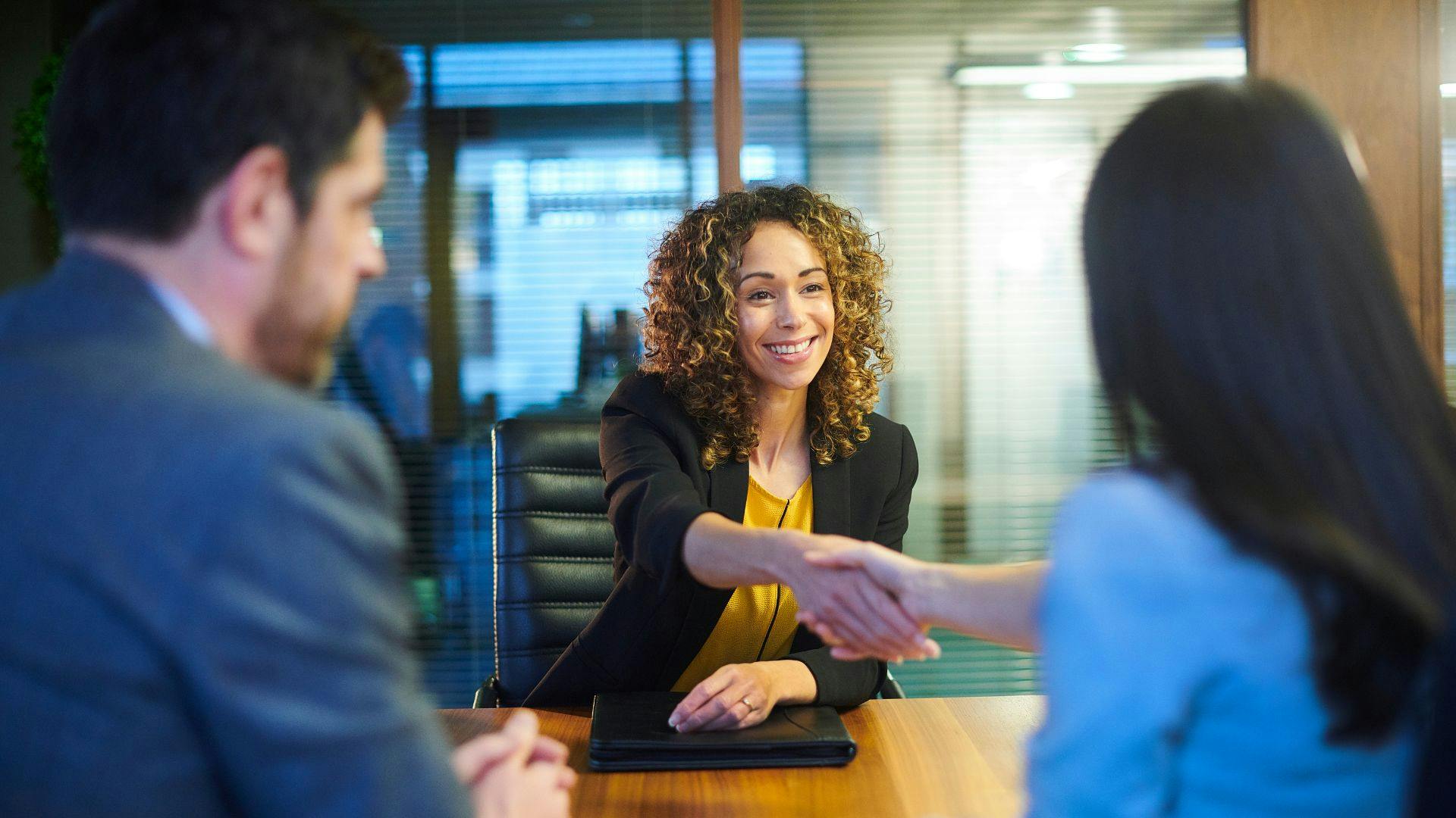 Office meeting: two women exchanging a handshake.