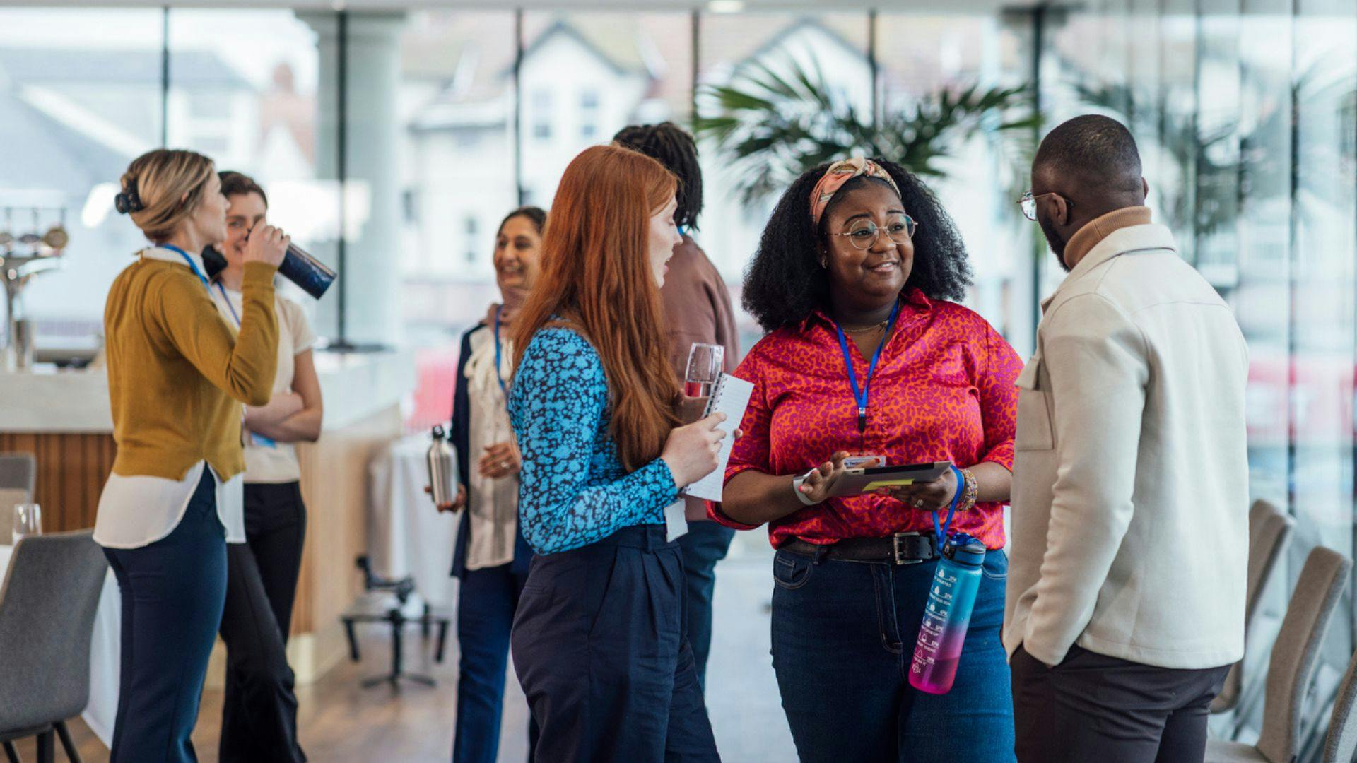 Several people conversing in a lobby, showcasing a lively atmosphere and diverse interactions among them.