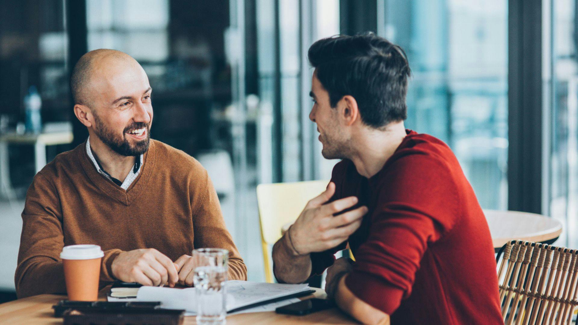 Two men conversing at a table, illustrating a moment of dialogue and connection between them.