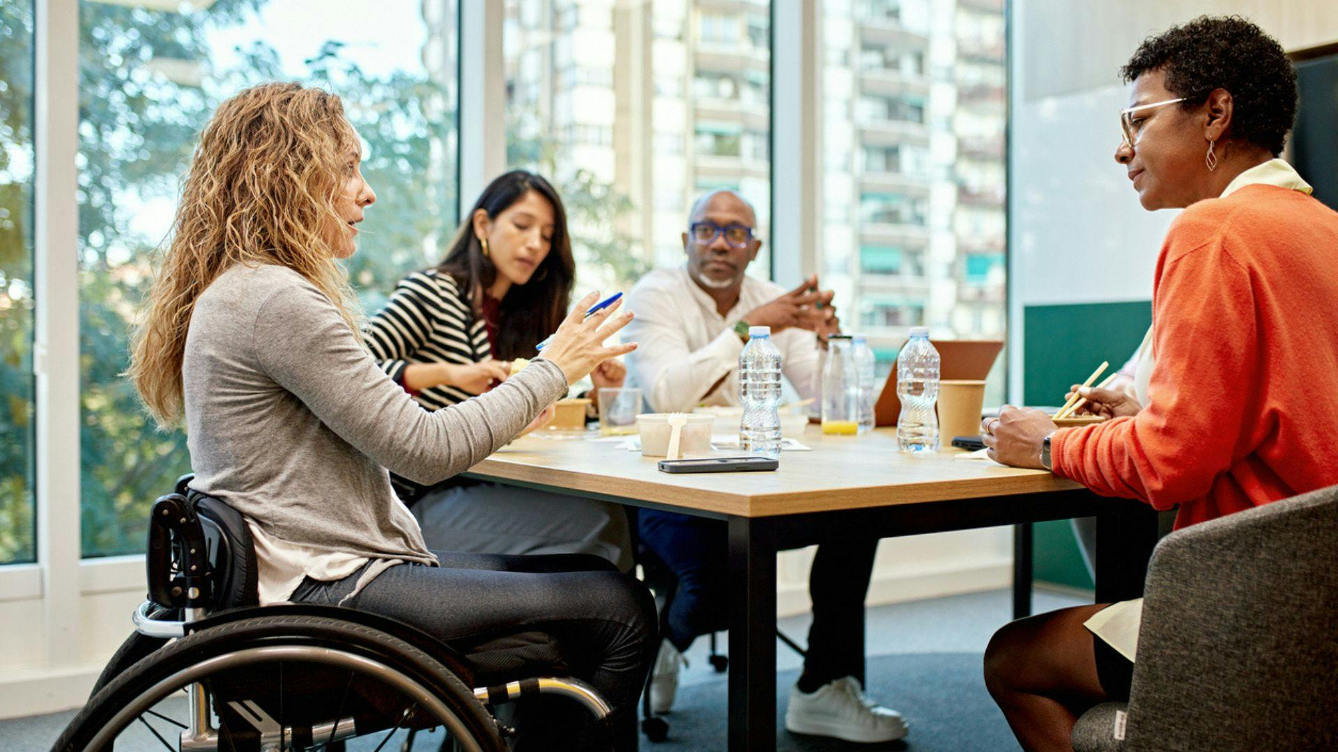 A woman participates in a gathering at a table with others, highlighting community and connection among friends.