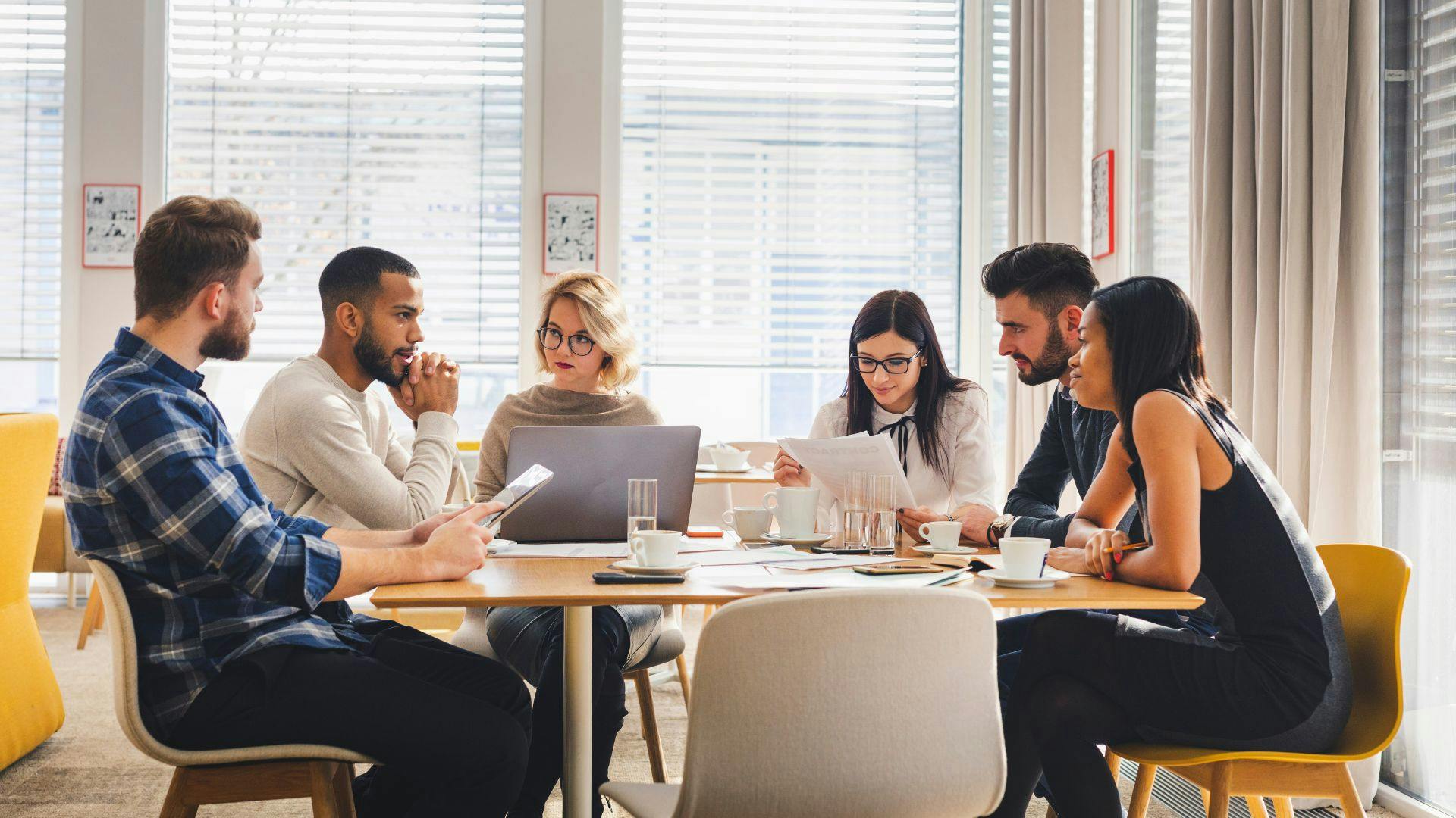 Several people seated at a table, focused on their laptops, fostering teamwork and collaboration in a modern workspace.