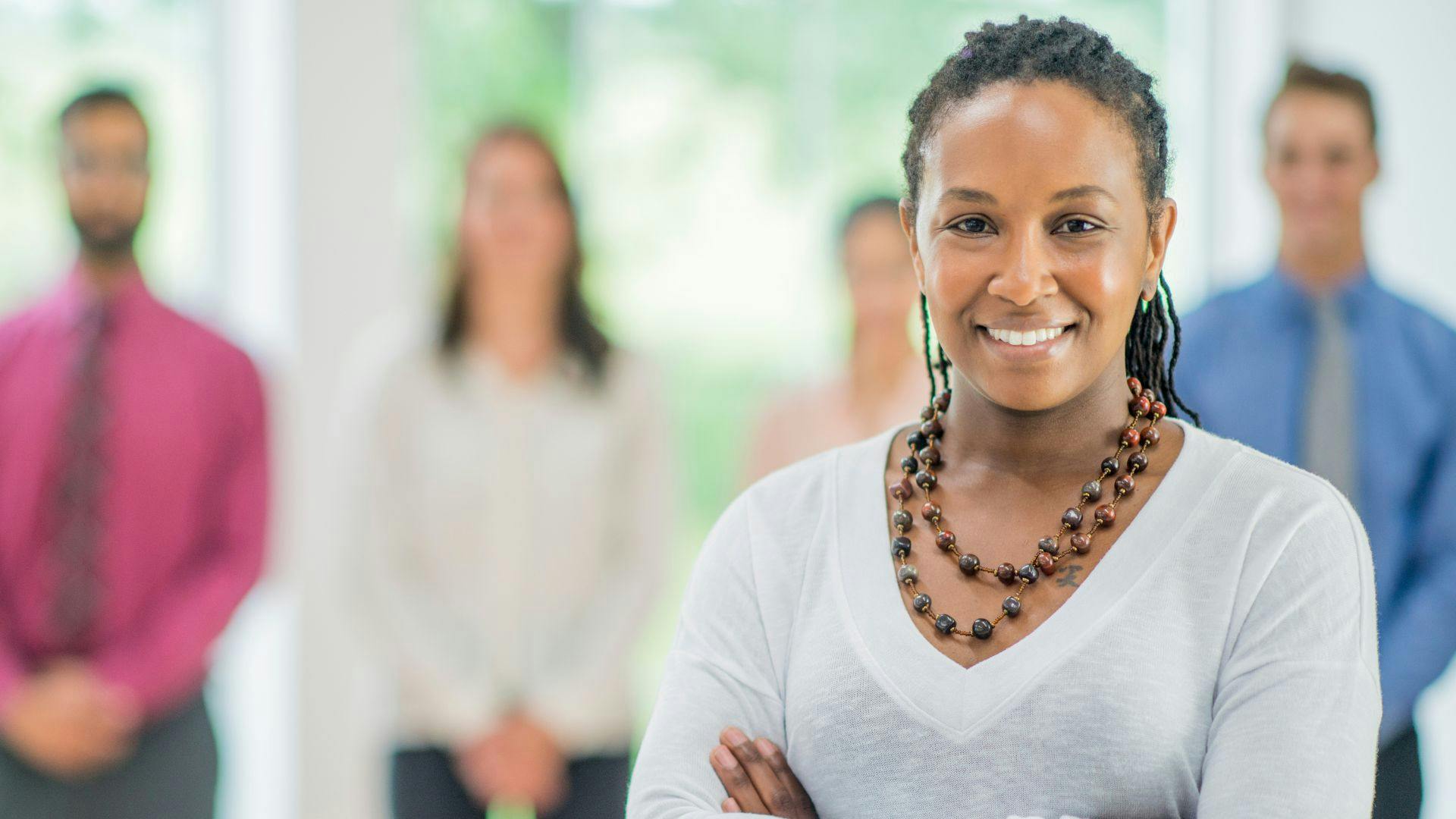 A woman stands confidently before a group of attentive individuals, engaging them with her presence and message.